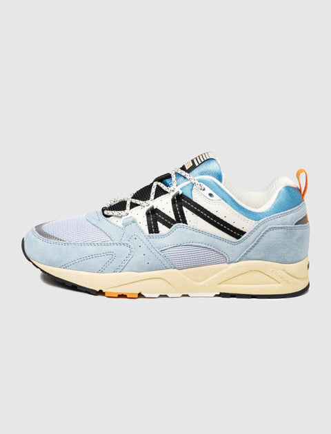 Light blue and white men's sneaker with black accents and beige sole on plain background