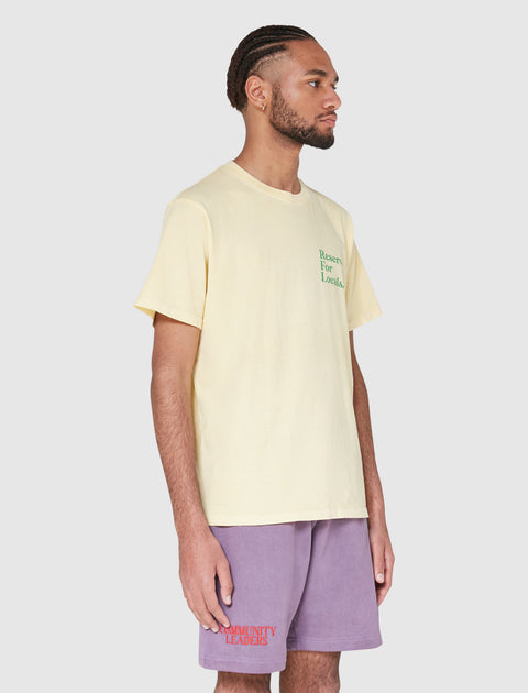 Man wearing light yellow Reserved For Locals tee and purple Community Leaders shorts