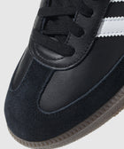 Close-up of black leather and suede sneaker with white stripes and gum sole