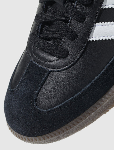 Close-up of black leather and suede sneaker with white stripes and gum sole