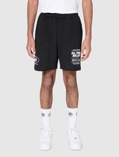 Black men's streetwear shorts with bold white graphic text, paired with white socks and sneakers.