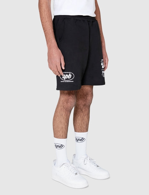 Man wearing black graphic streetwear shorts, white logo socks, and white sneakers